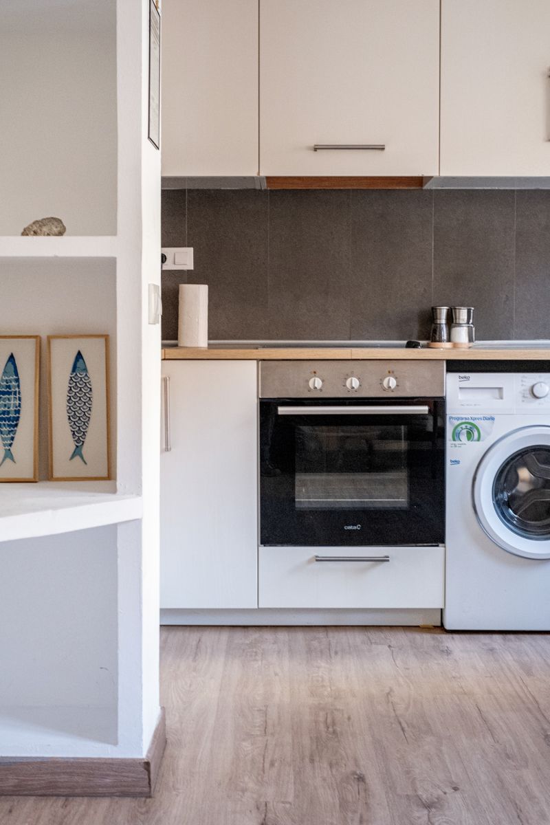 A kitchen with white cabinets and a washer and dryer