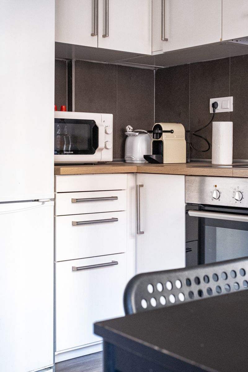 A kitchen with white cabinets and a microwave oven