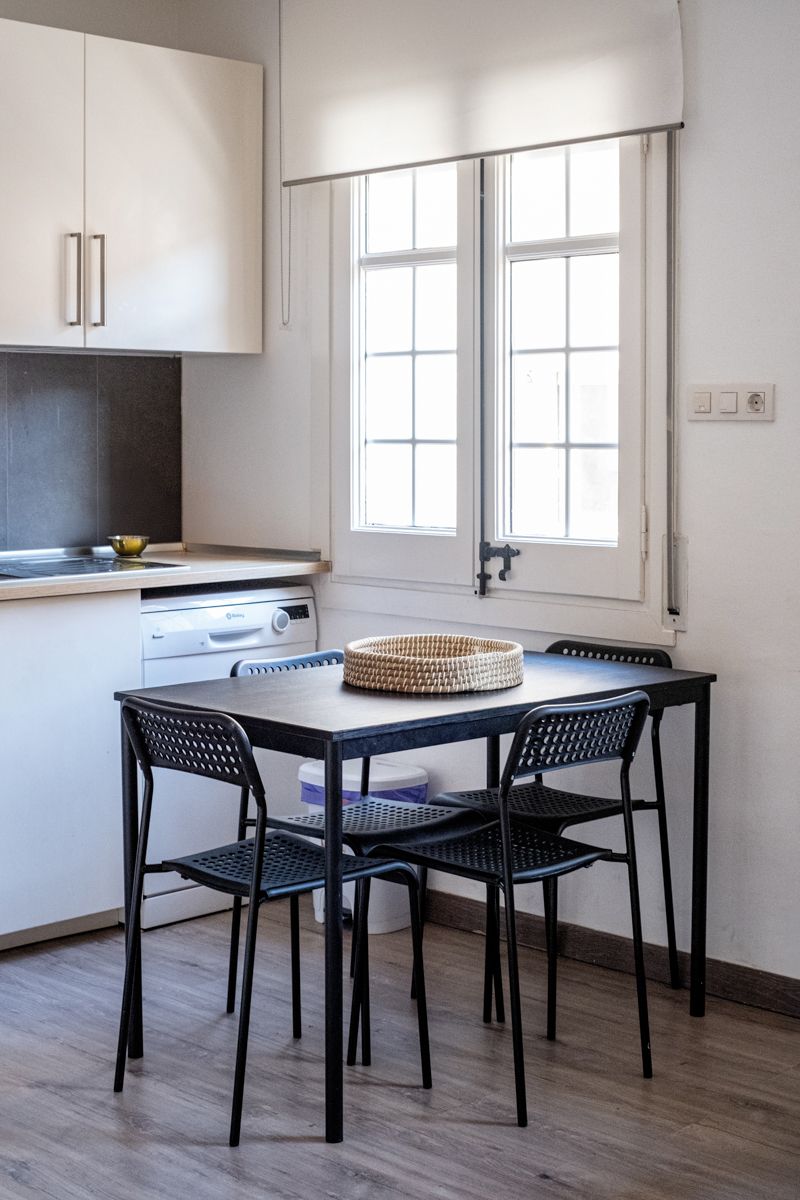 A kitchen with a table and chairs in front of a window.