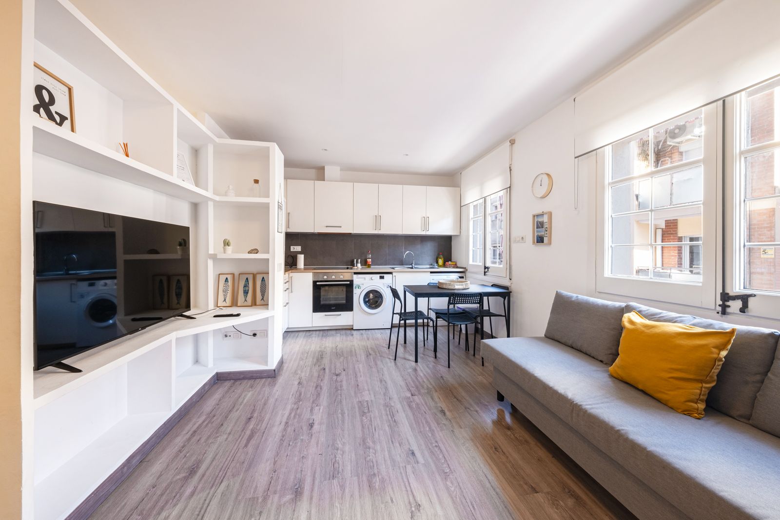 A living room with a couch , television , and kitchen.