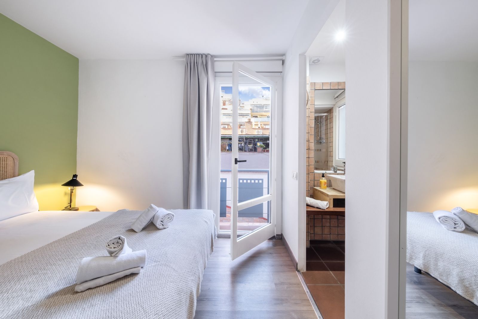 A hotel room with two beds and a sliding glass door leading to a balcony.