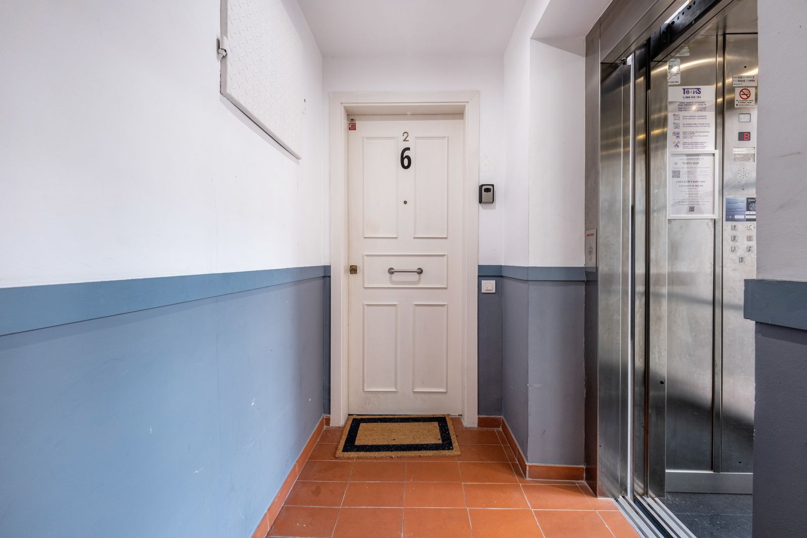 A hallway with a door and an elevator in a building.