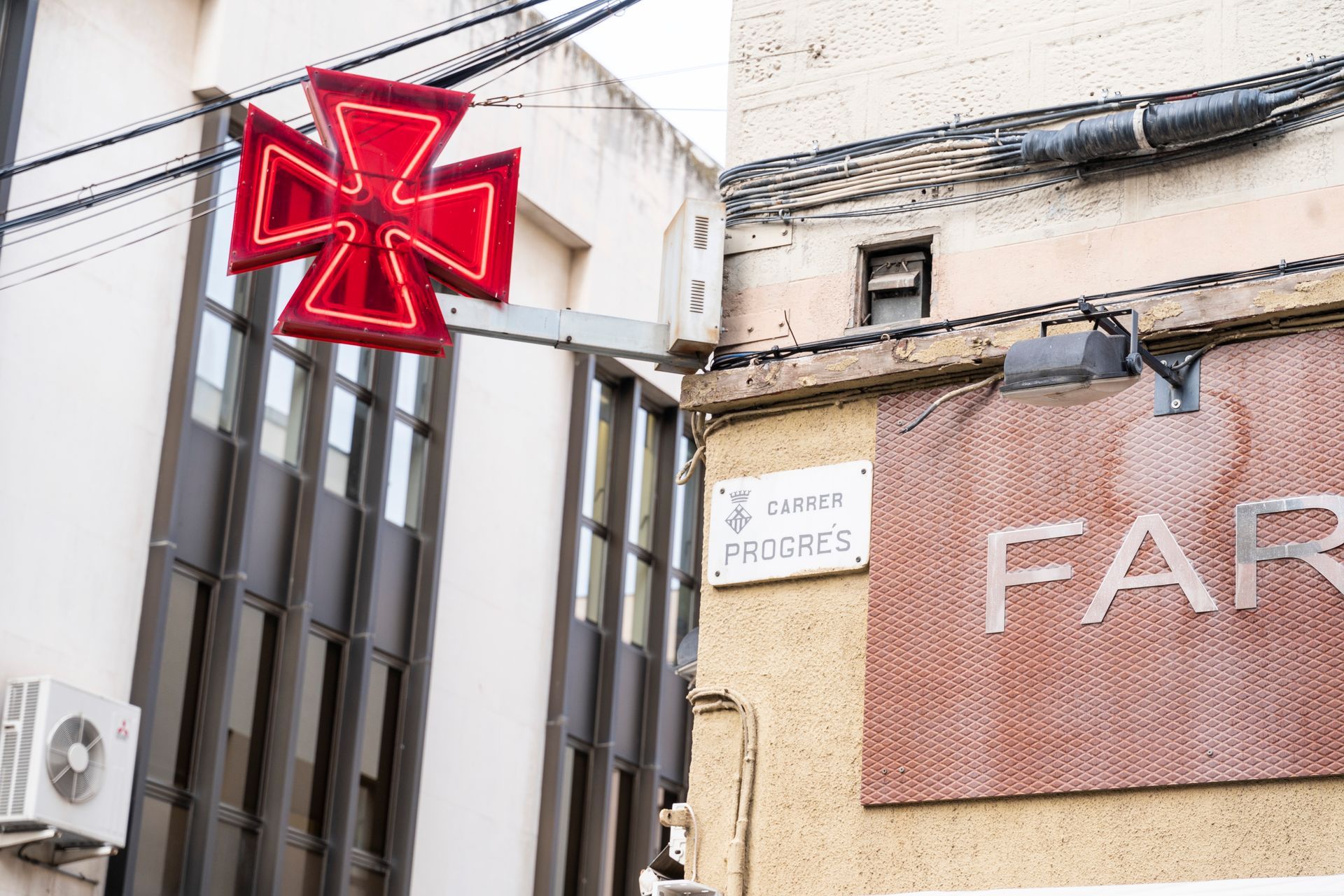 A red cross is hanging from a power line next to a sign that says far