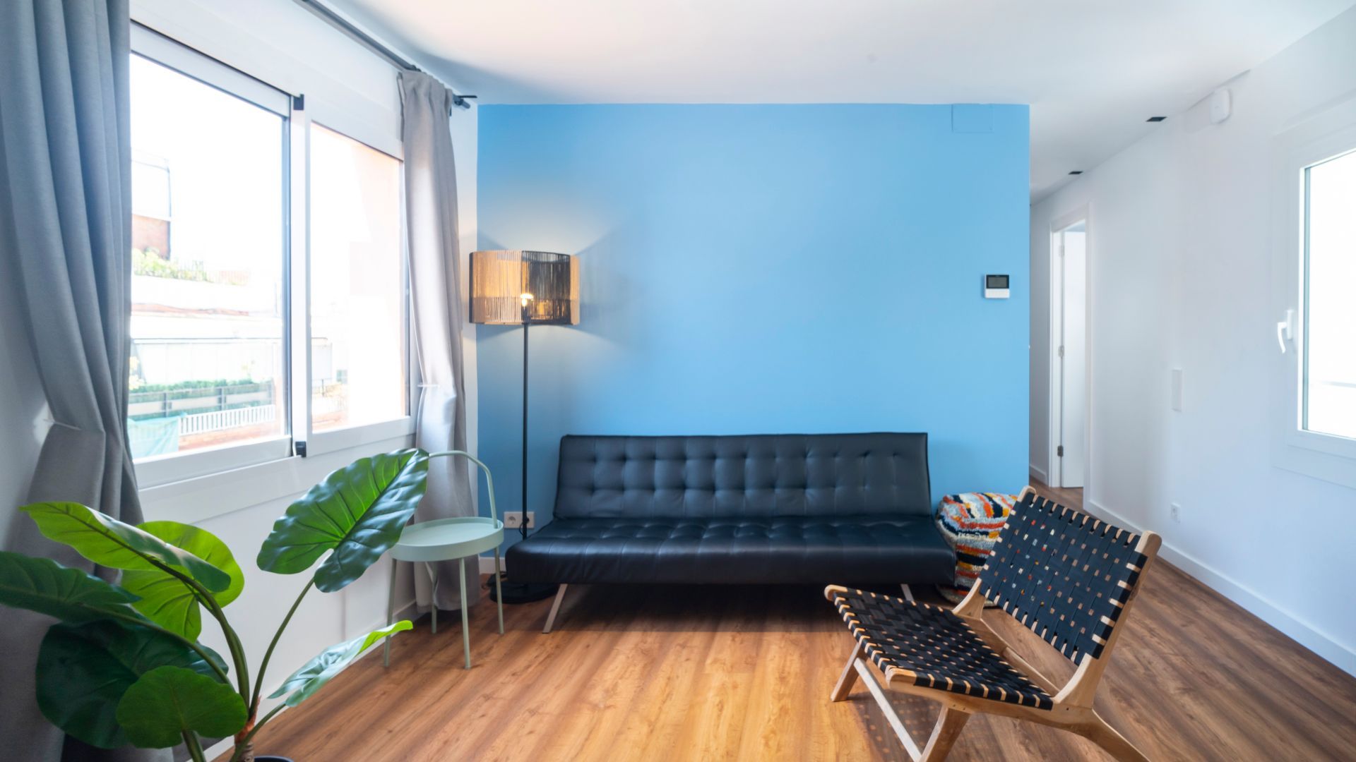 A living room with a blue wall and a black couch.