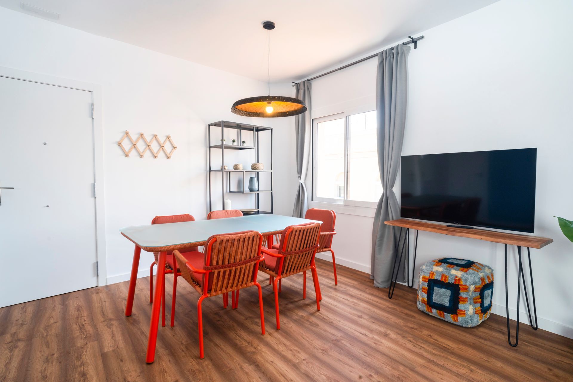 A living room with a table and chairs and a flat screen tv.