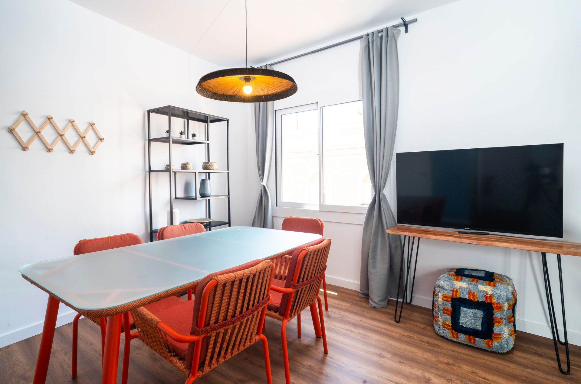 A dining room with a table and chairs and a flat screen tv.
