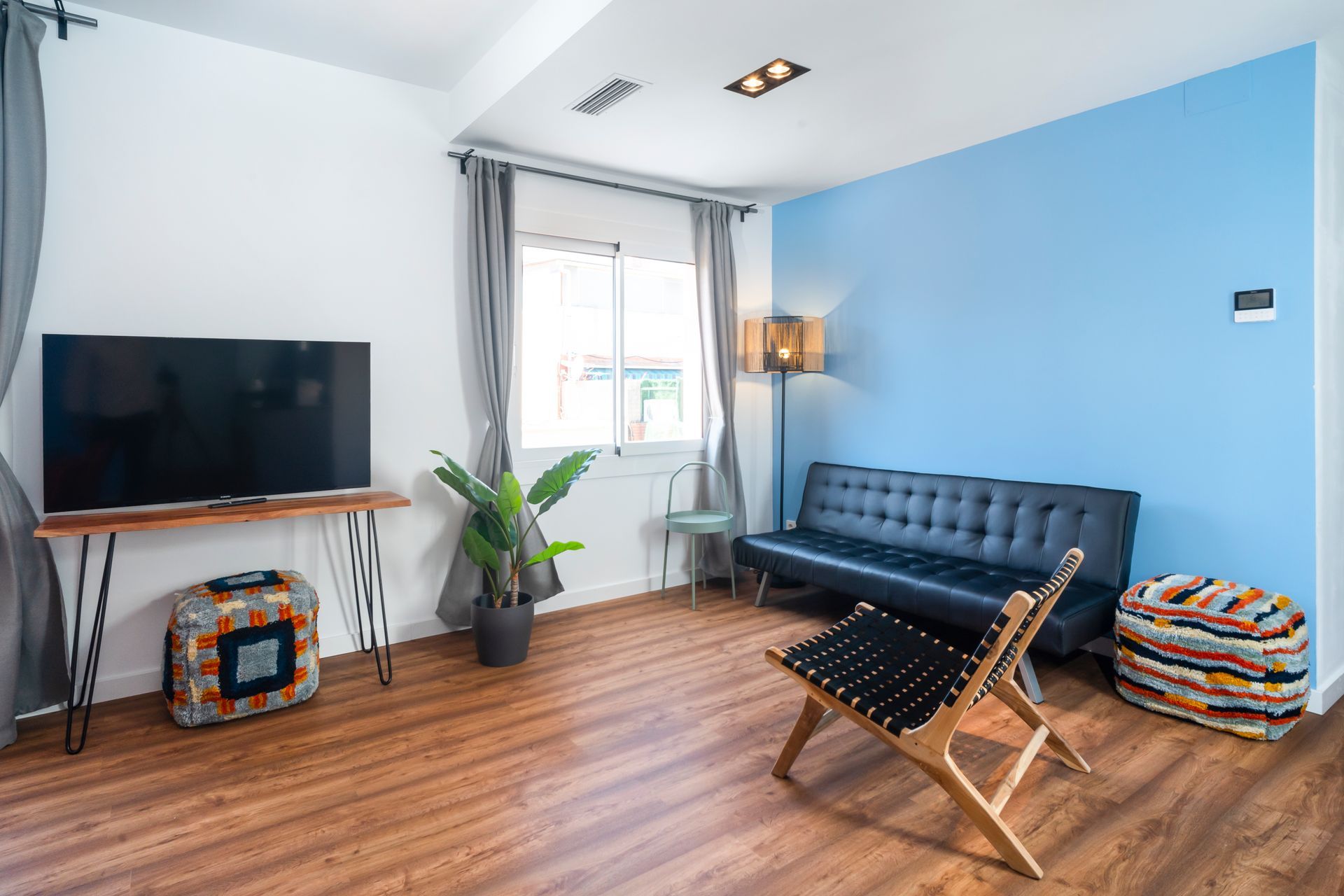 A living room with a couch , chair , television and blue walls.