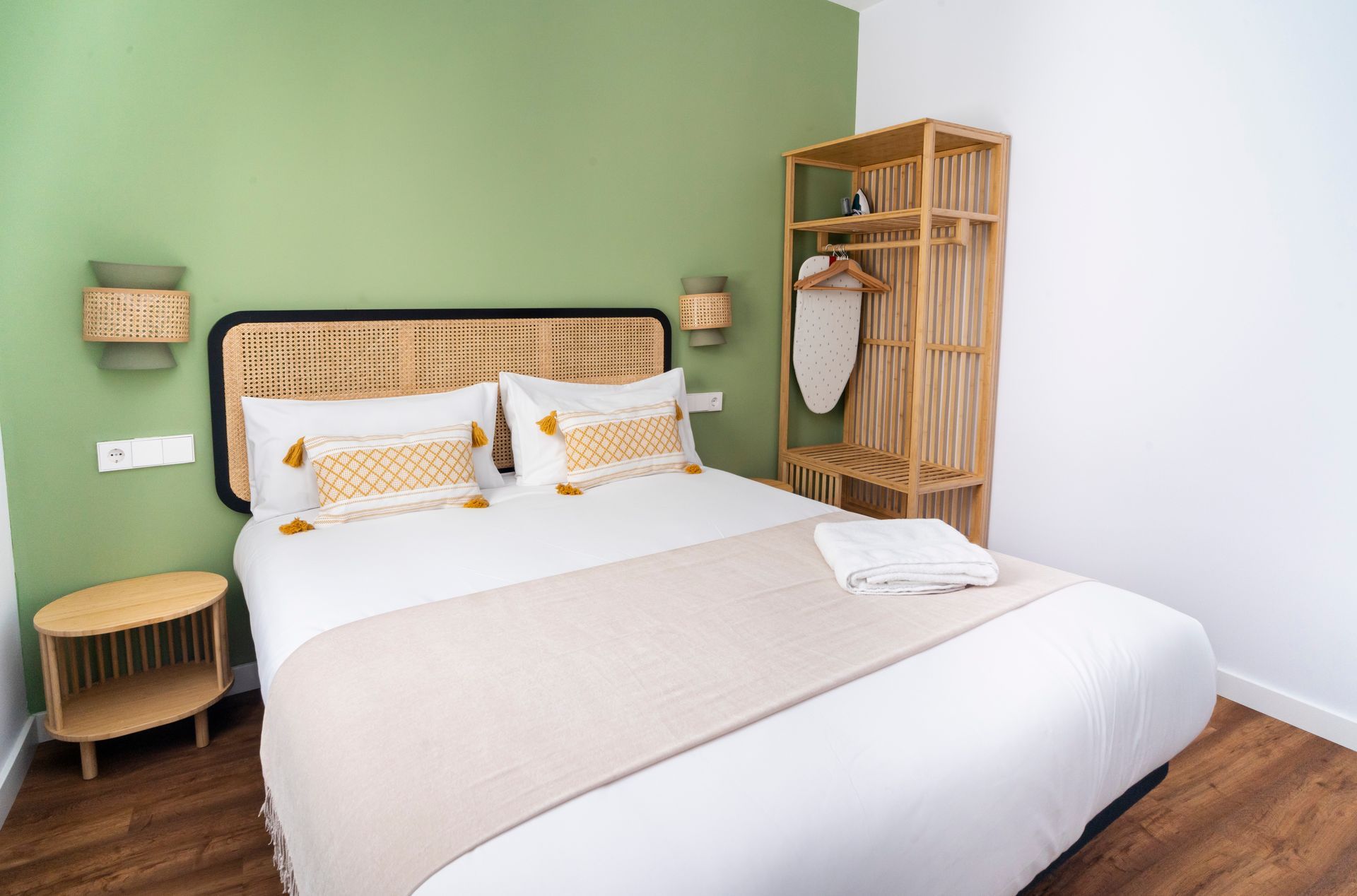 A bedroom with a bed , nightstand , dresser and green wall.
