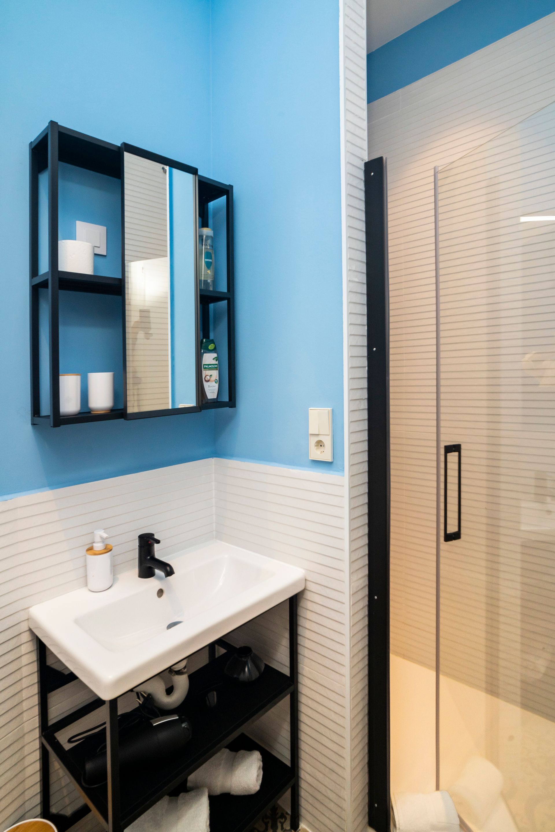 A bathroom with a sink , mirror and shower.