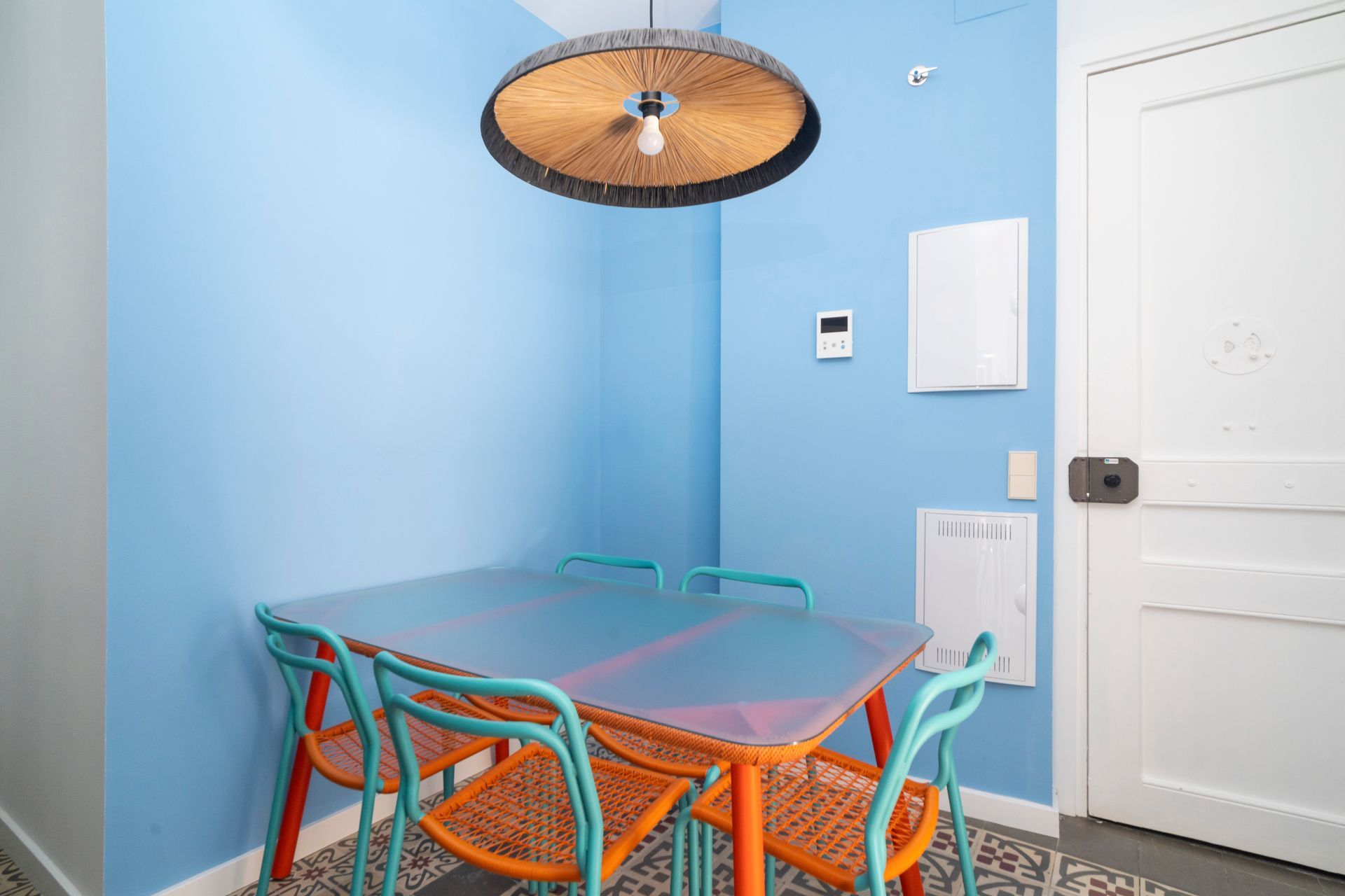 A dining room with a table and chairs and a blue wall.
