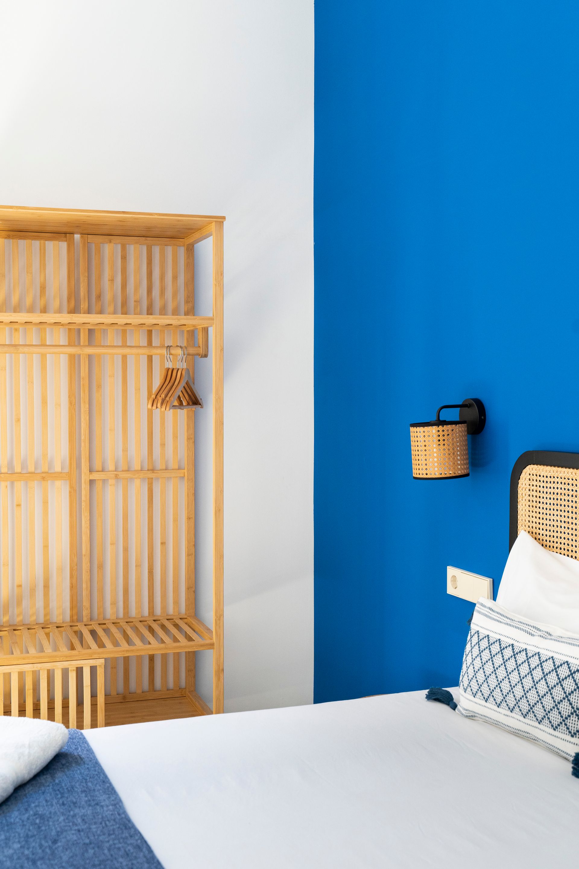 A bedroom with a bed , a wooden shelf , and a blue wall.
