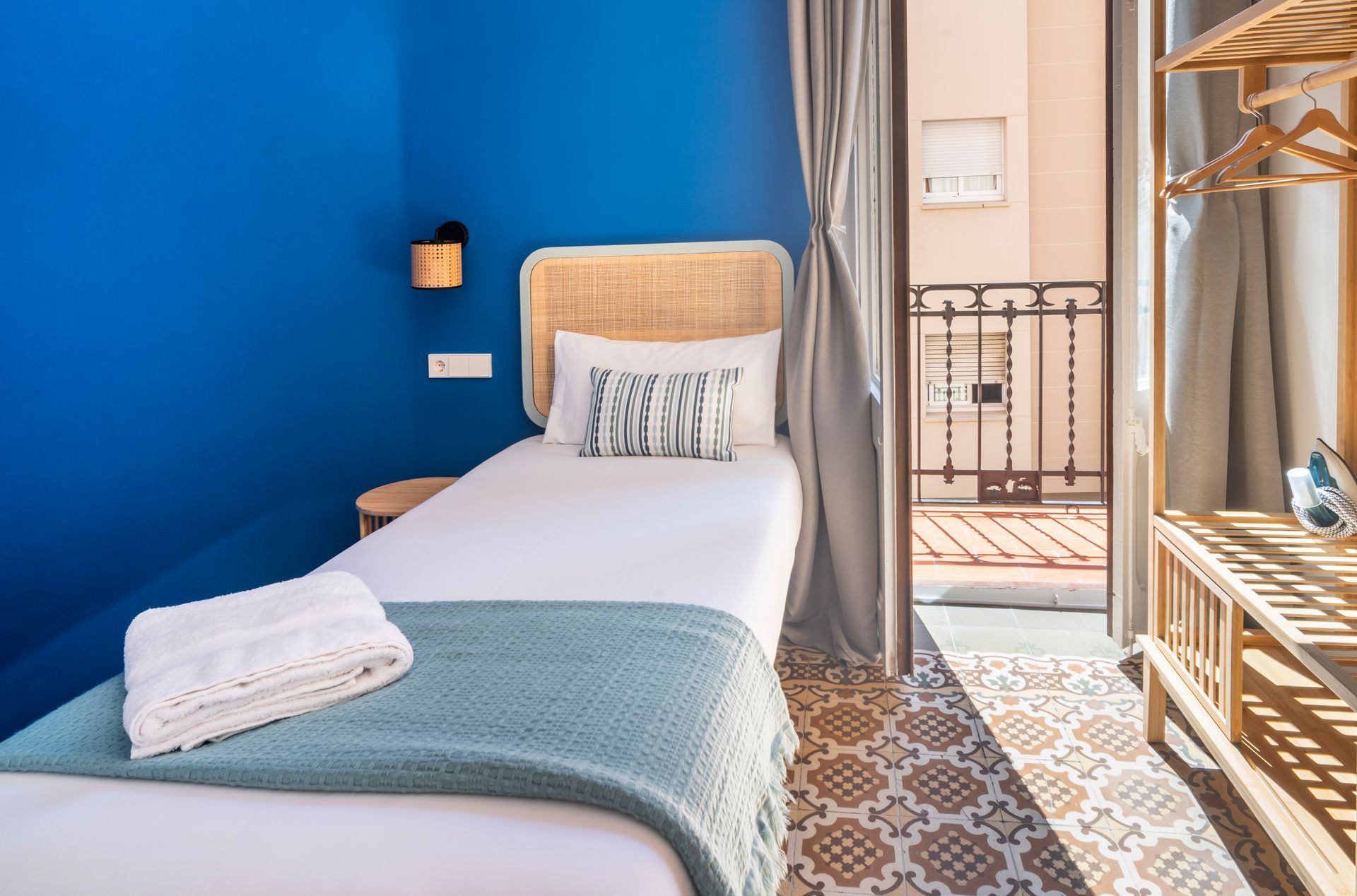 A bedroom with a single bed and a balcony.