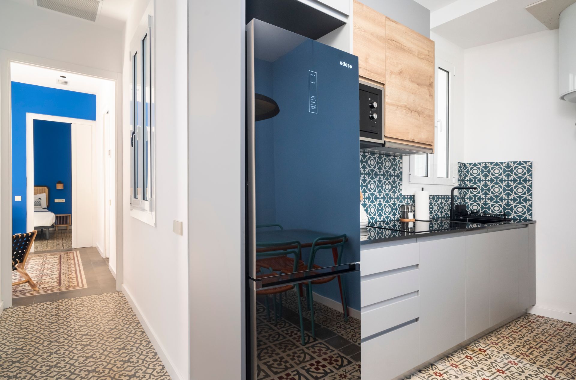 A kitchen with a blue refrigerator and white cabinets.
