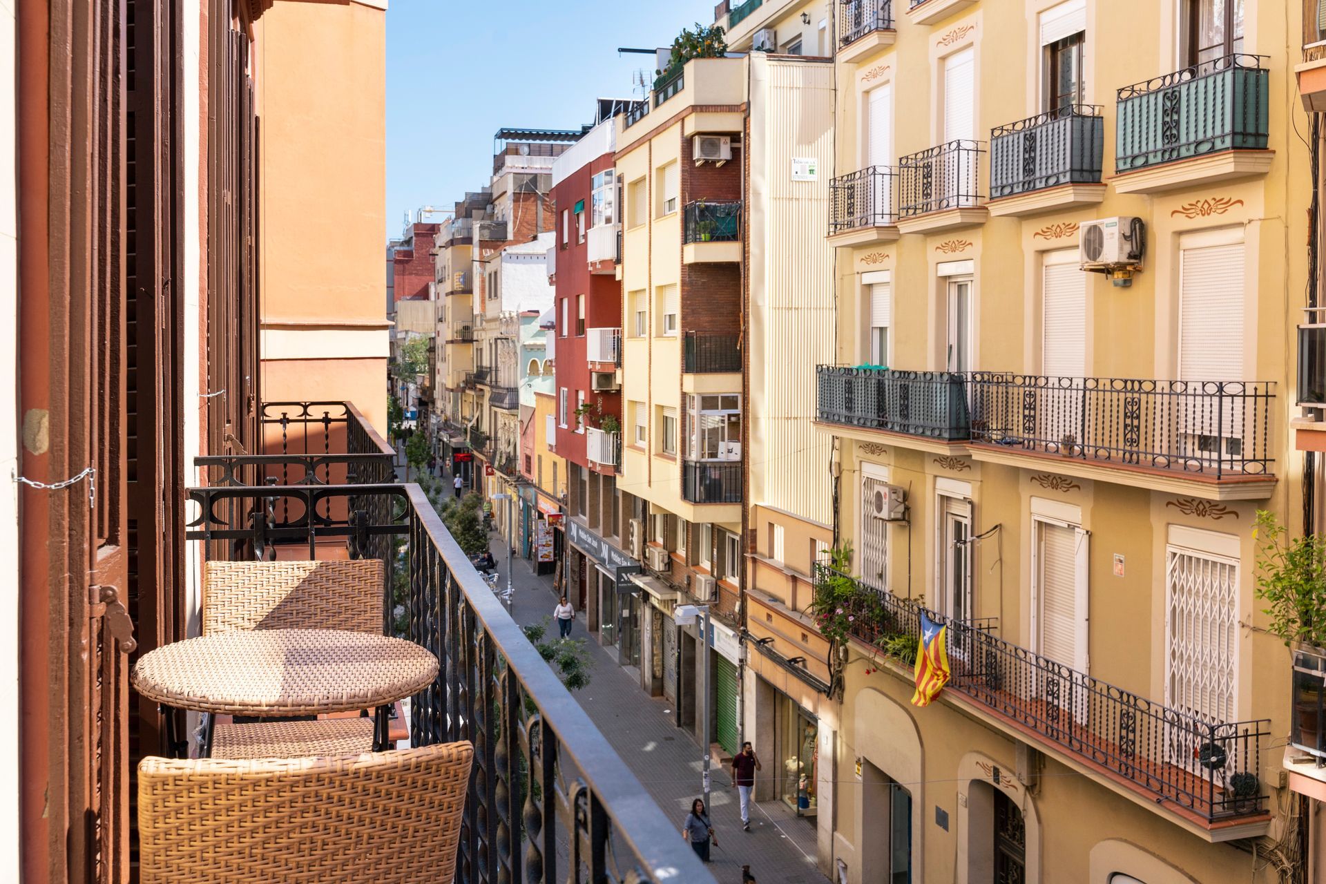 A balcony with a table and chairs overlooking a city street.