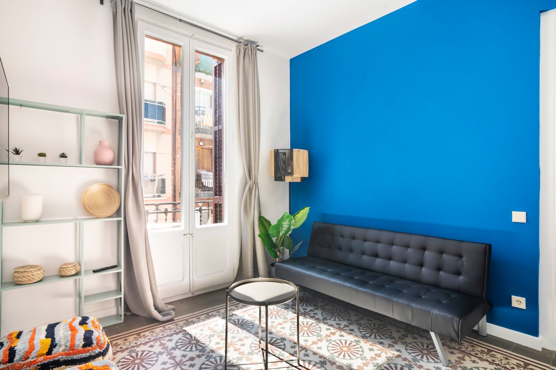 A living room with a blue wall and a black couch.