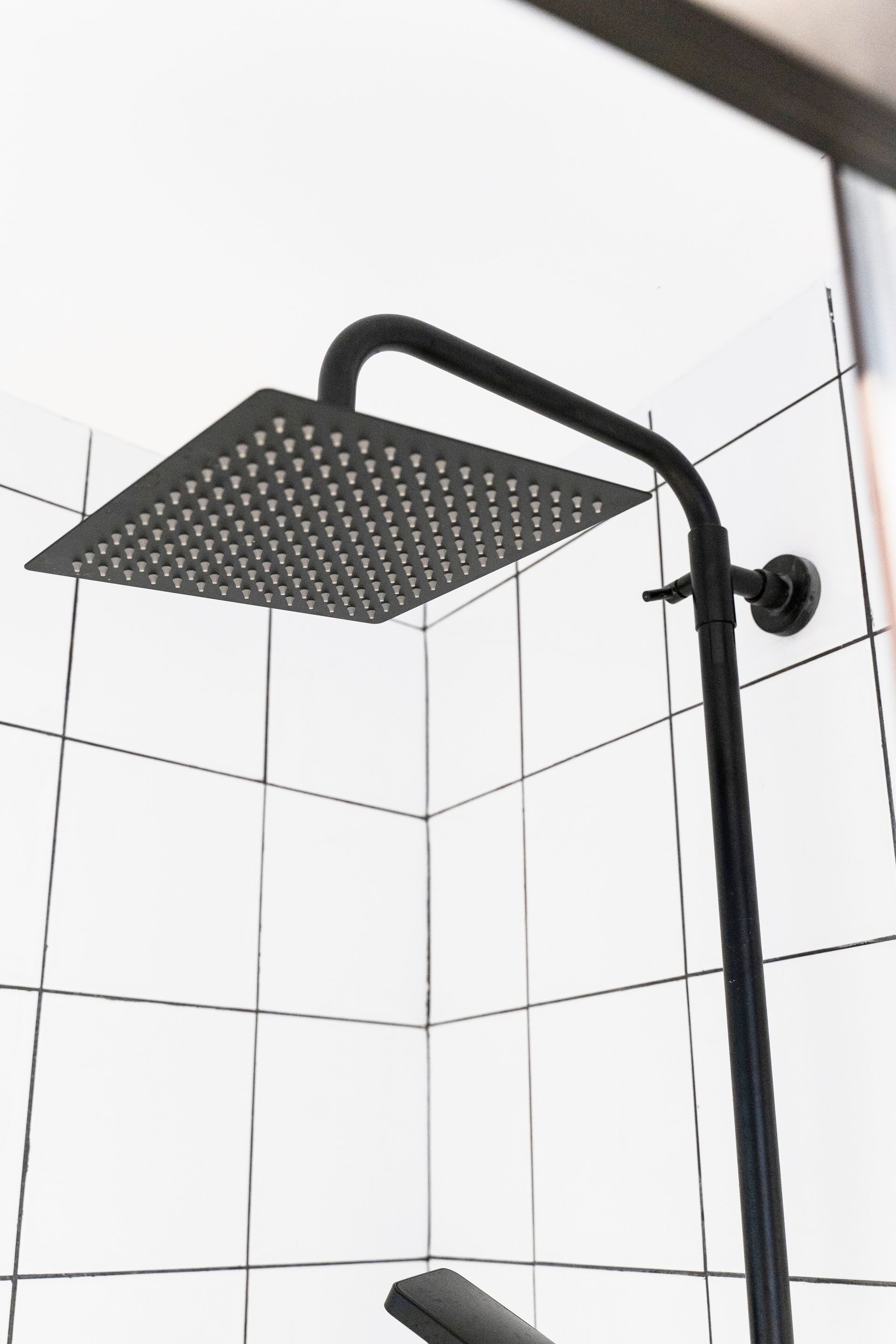 A shower head is hanging from the ceiling in a bathroom.