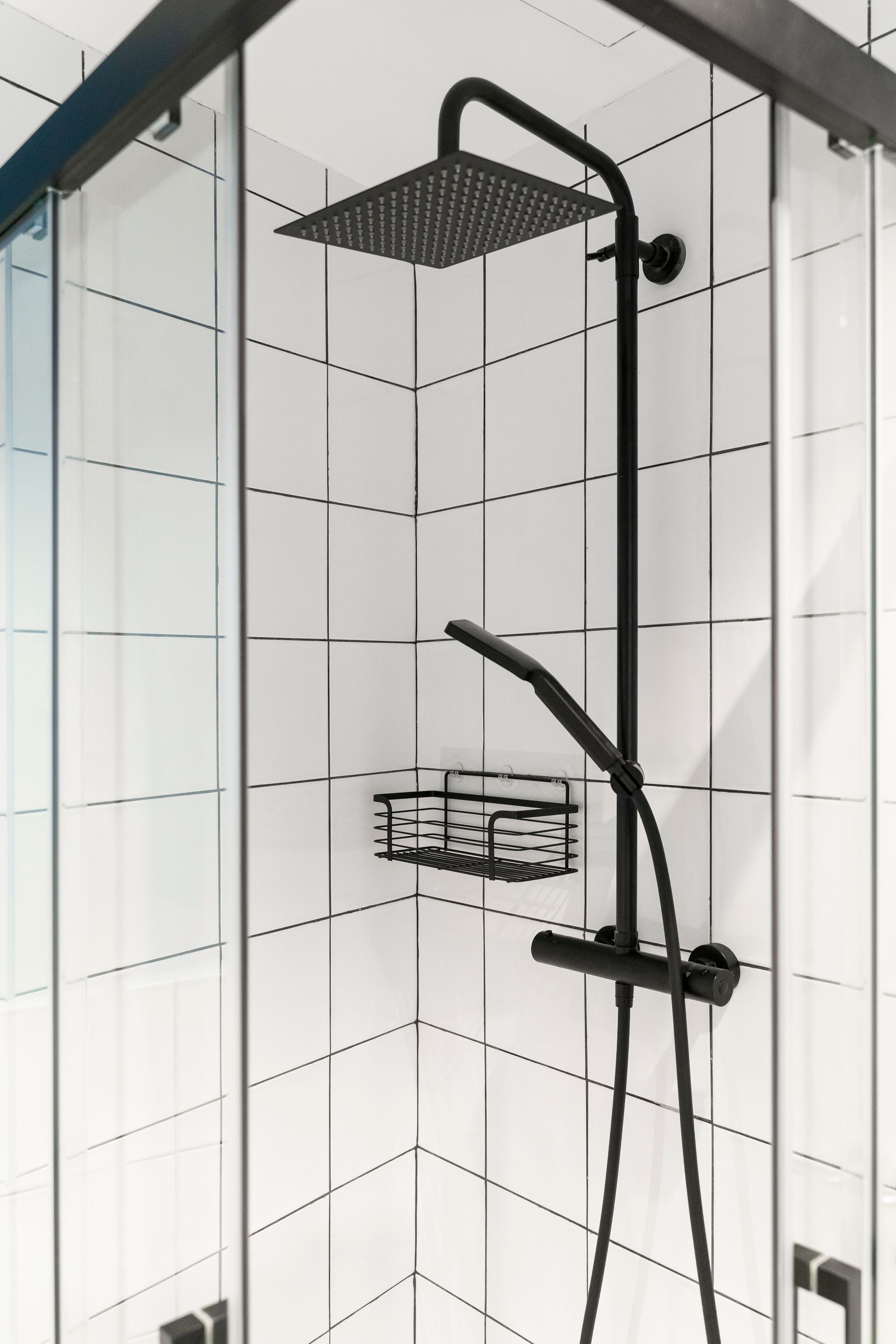 A black shower head in a bathroom with white tiles