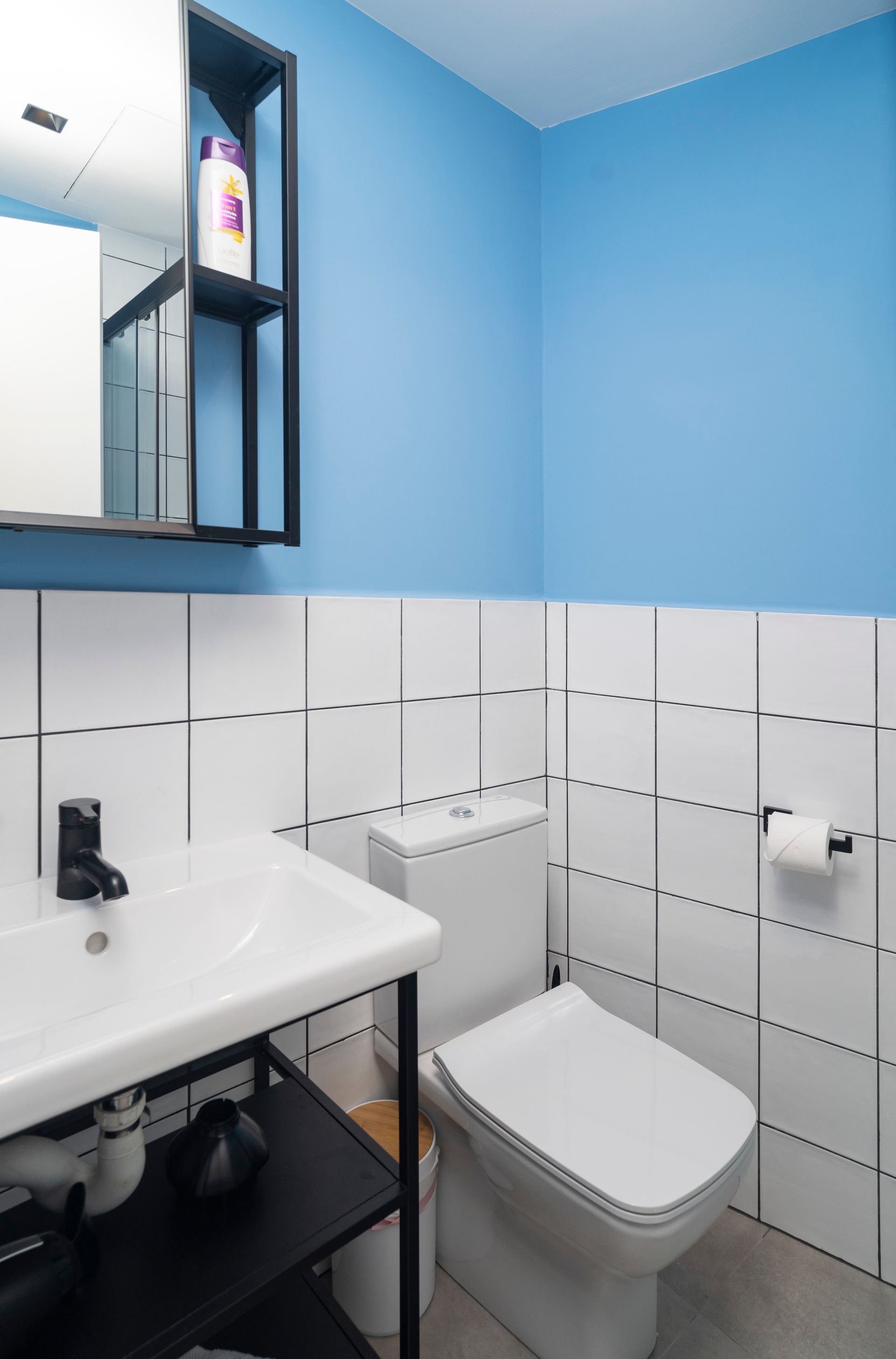 A bathroom with a toilet , sink , mirror and blue walls