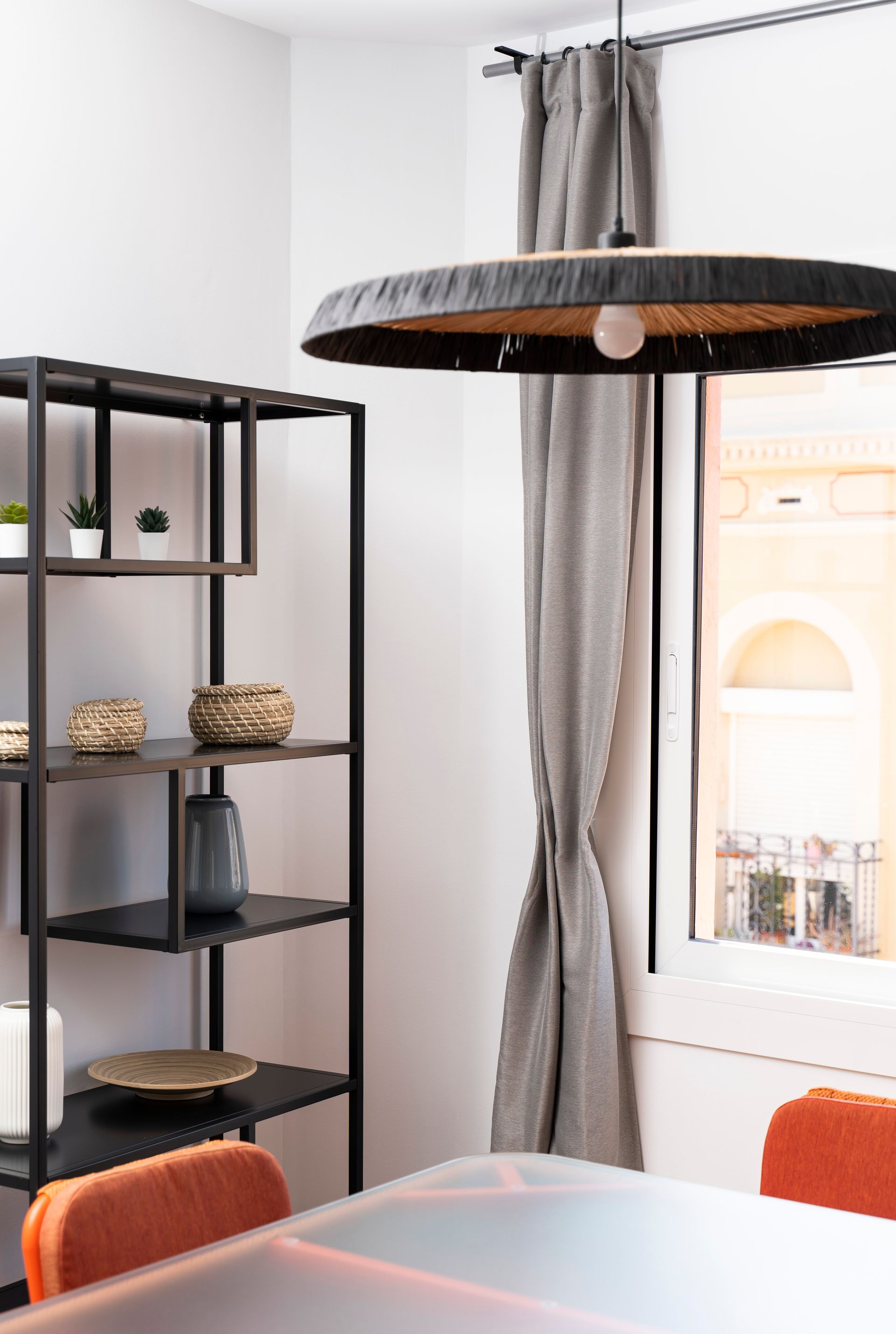 A dining room with a table and chairs and a shelf