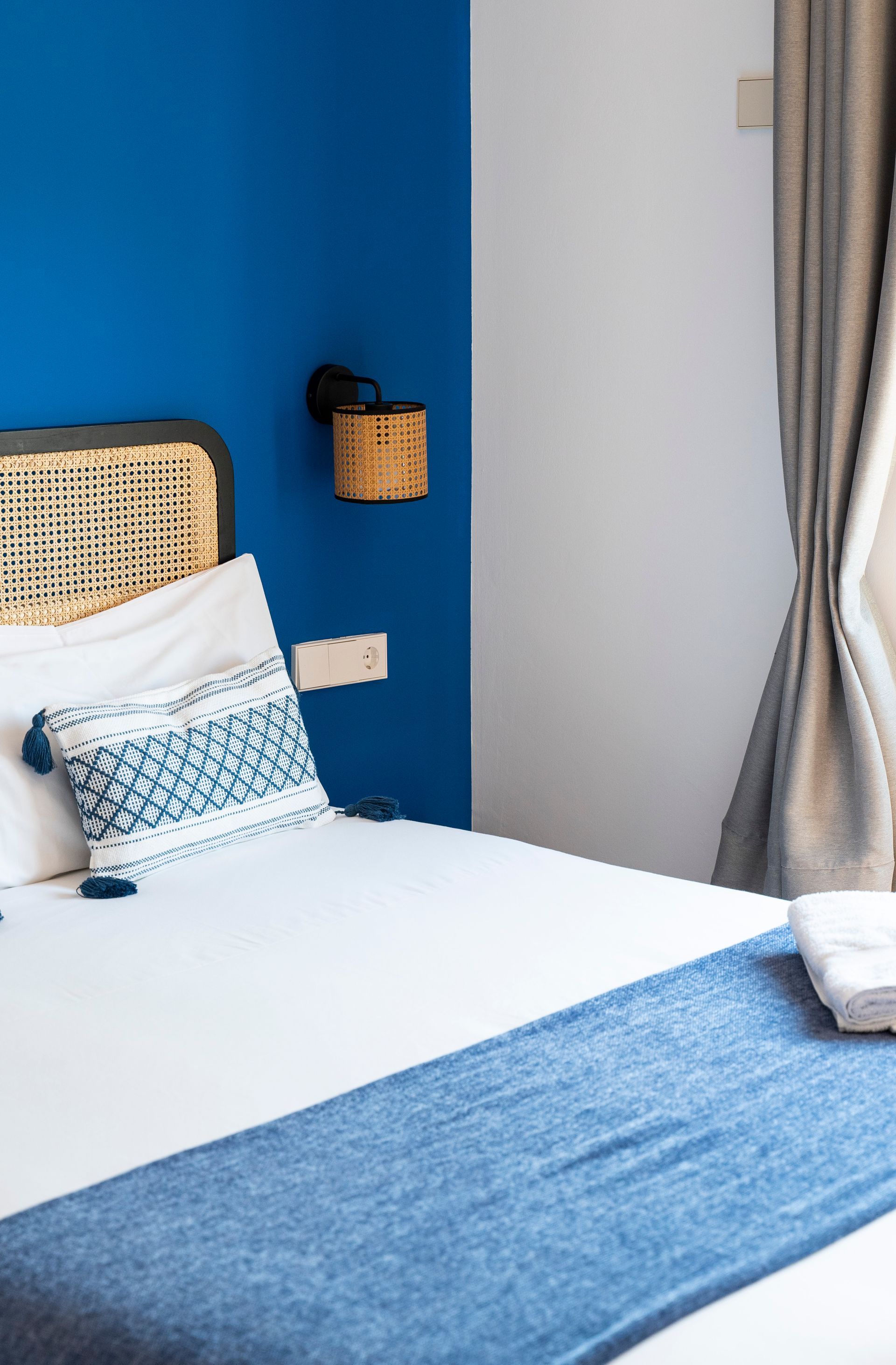 A bedroom with a blue wall and a bed with a blue blanket on it.