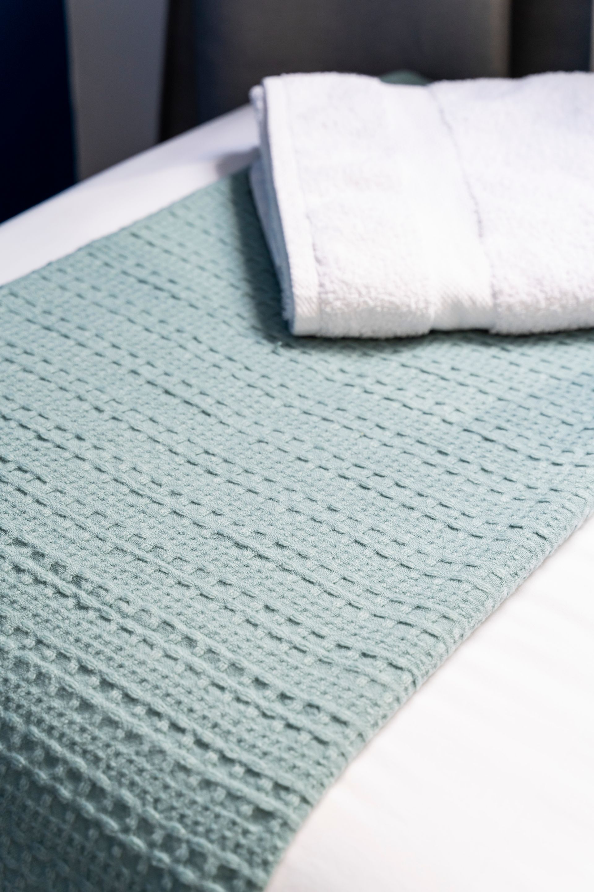 A bed with a blanket and two towels on it.