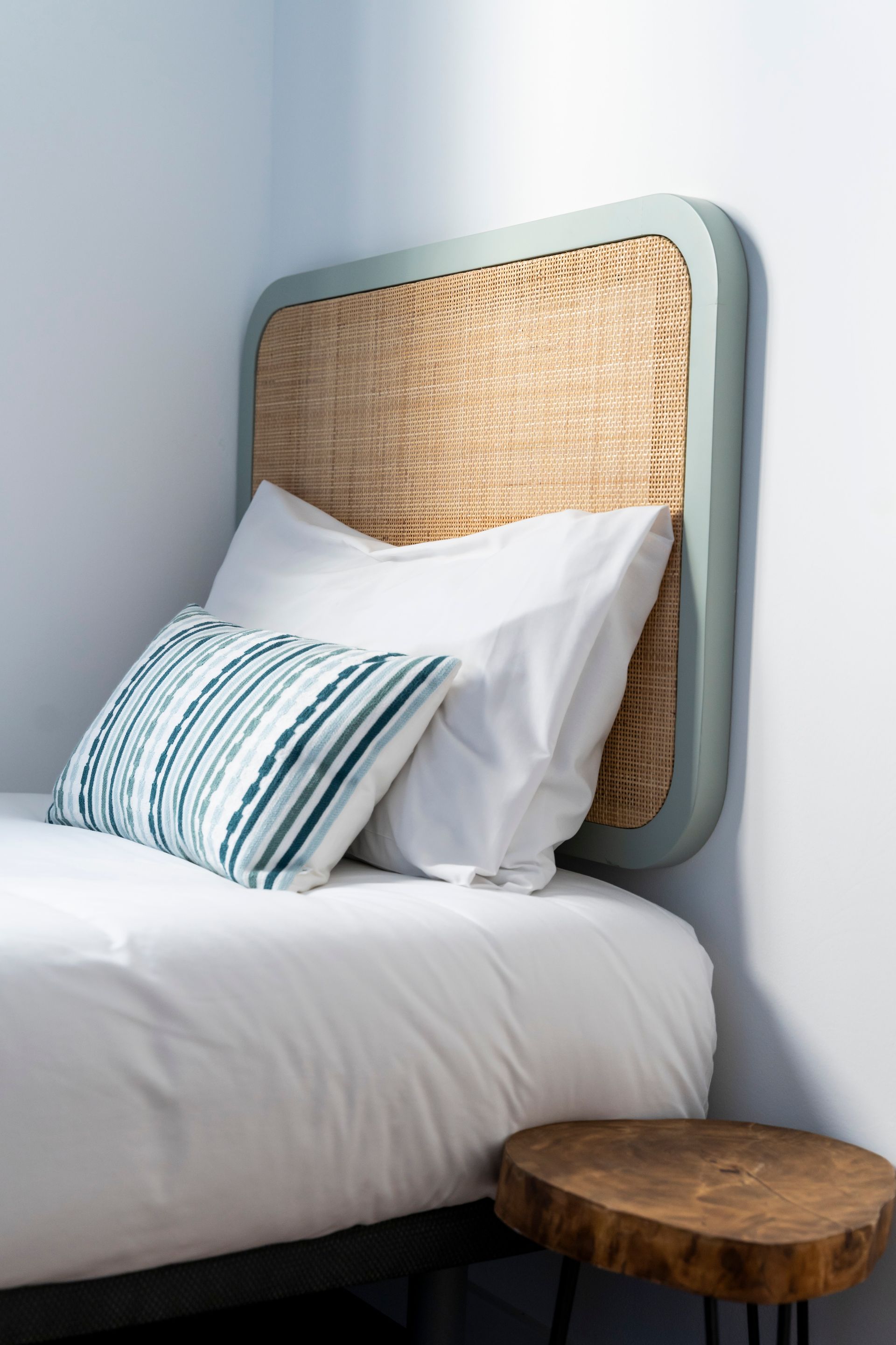 A bed with a wicker headboard and pillows on it.