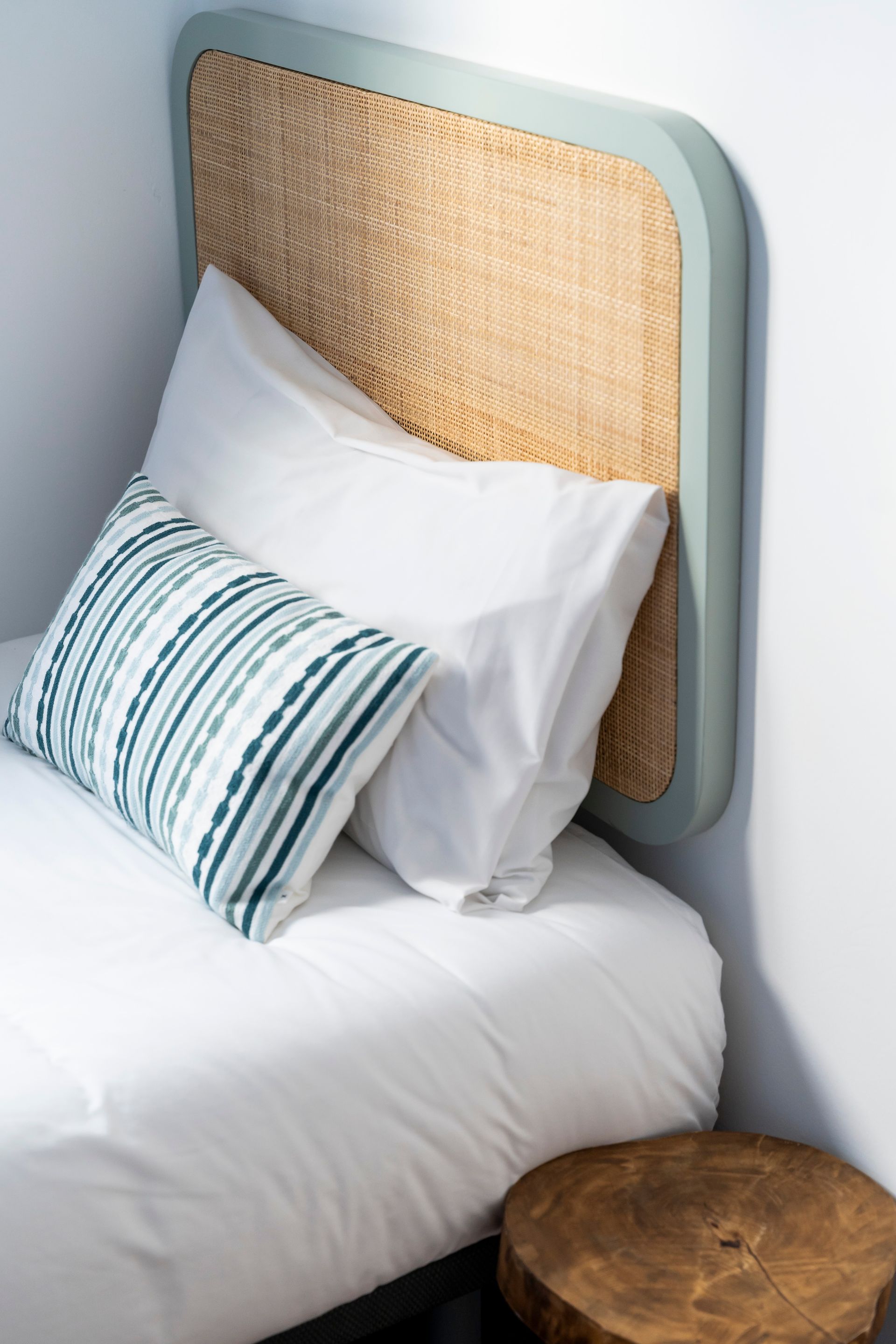 A bed with a wicker headboard and pillows on it.