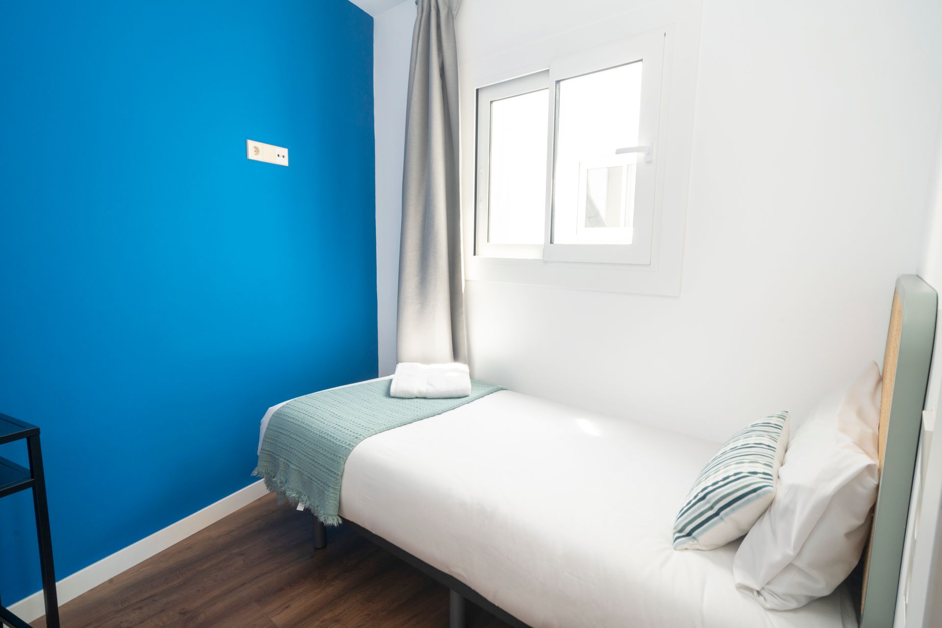 A bedroom with a single bed and a blue wall.