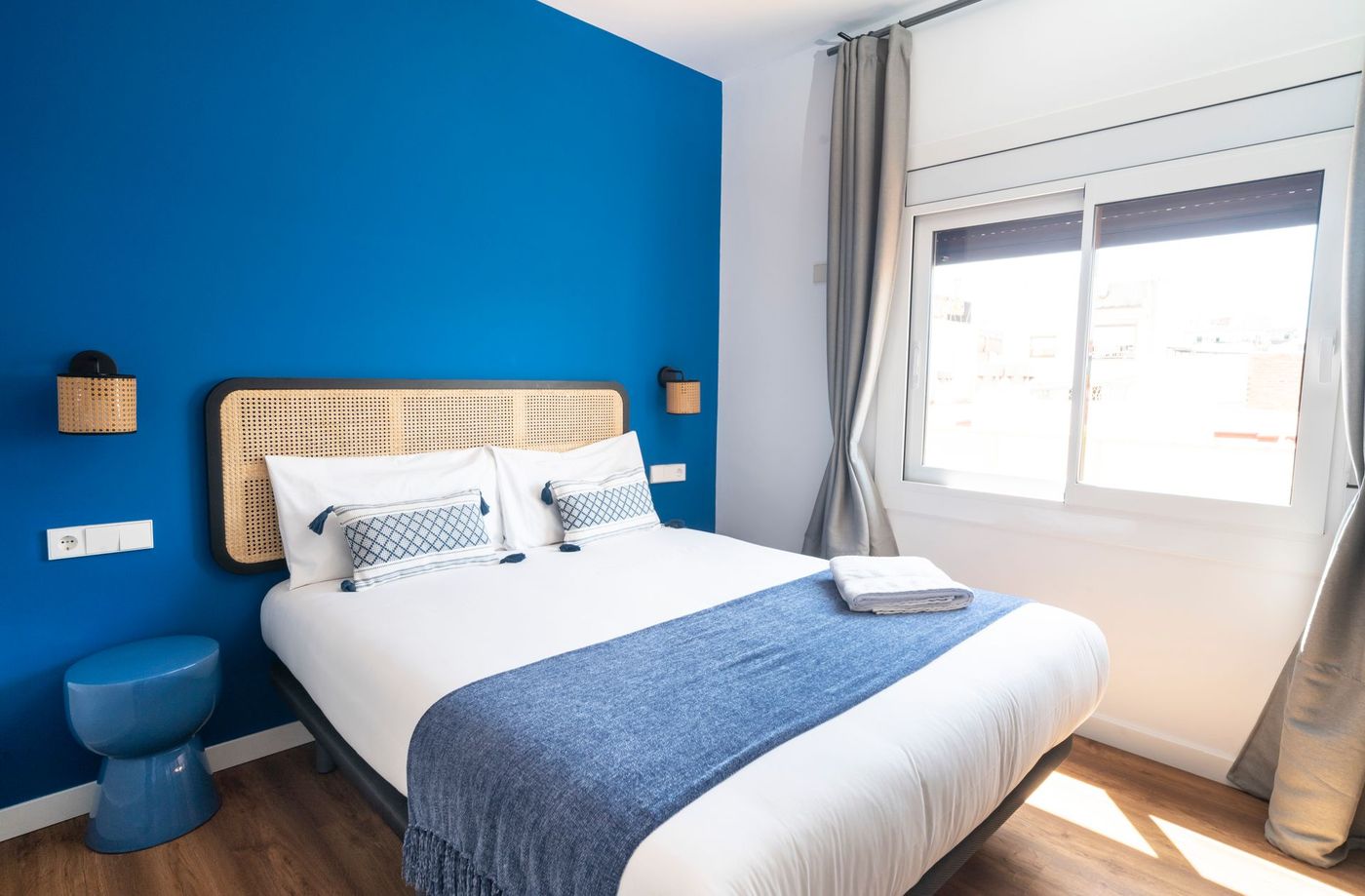 A bedroom with a bed , blue walls and a window.