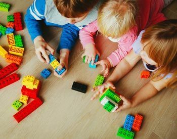 A group of children are playing with lego blocks on the floor.