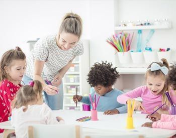 A teacher is teaching a group of children how to draw.