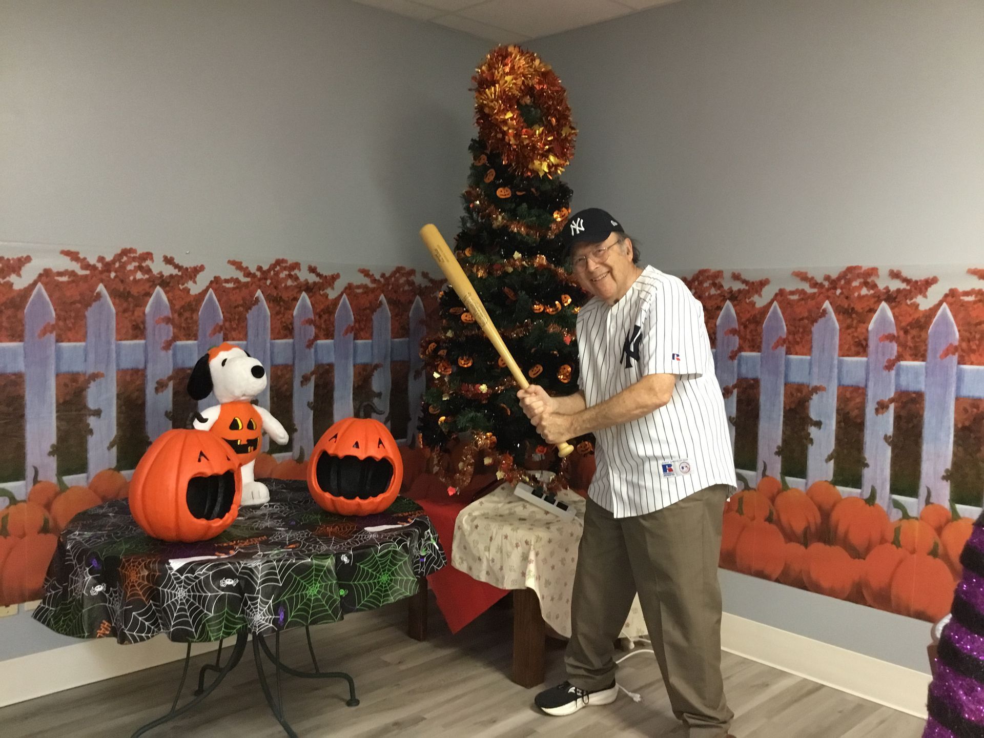 A man is holding a baseball bat in front of a christmas tree.