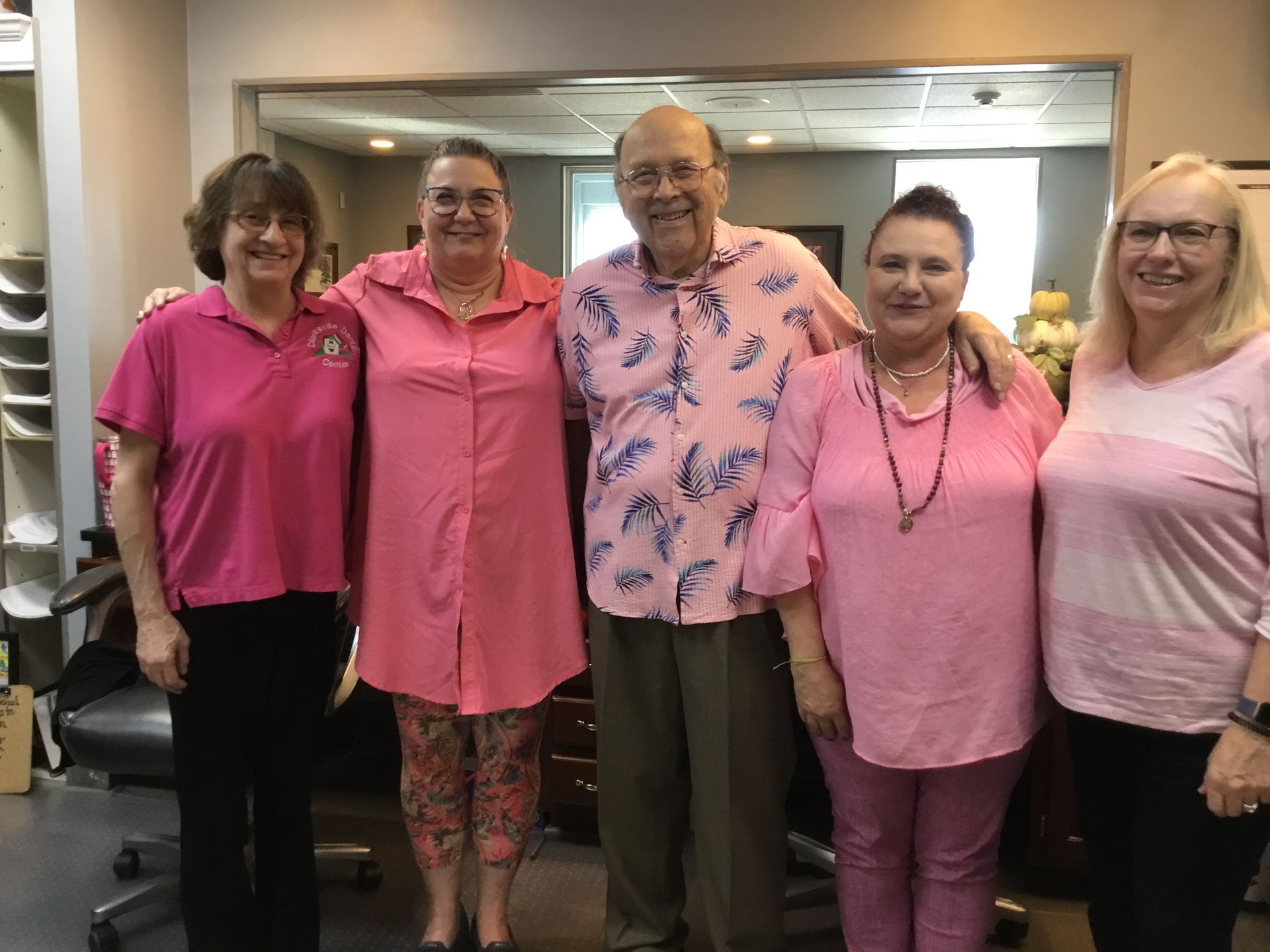 A group of people wearing pink shirts are posing for a picture.