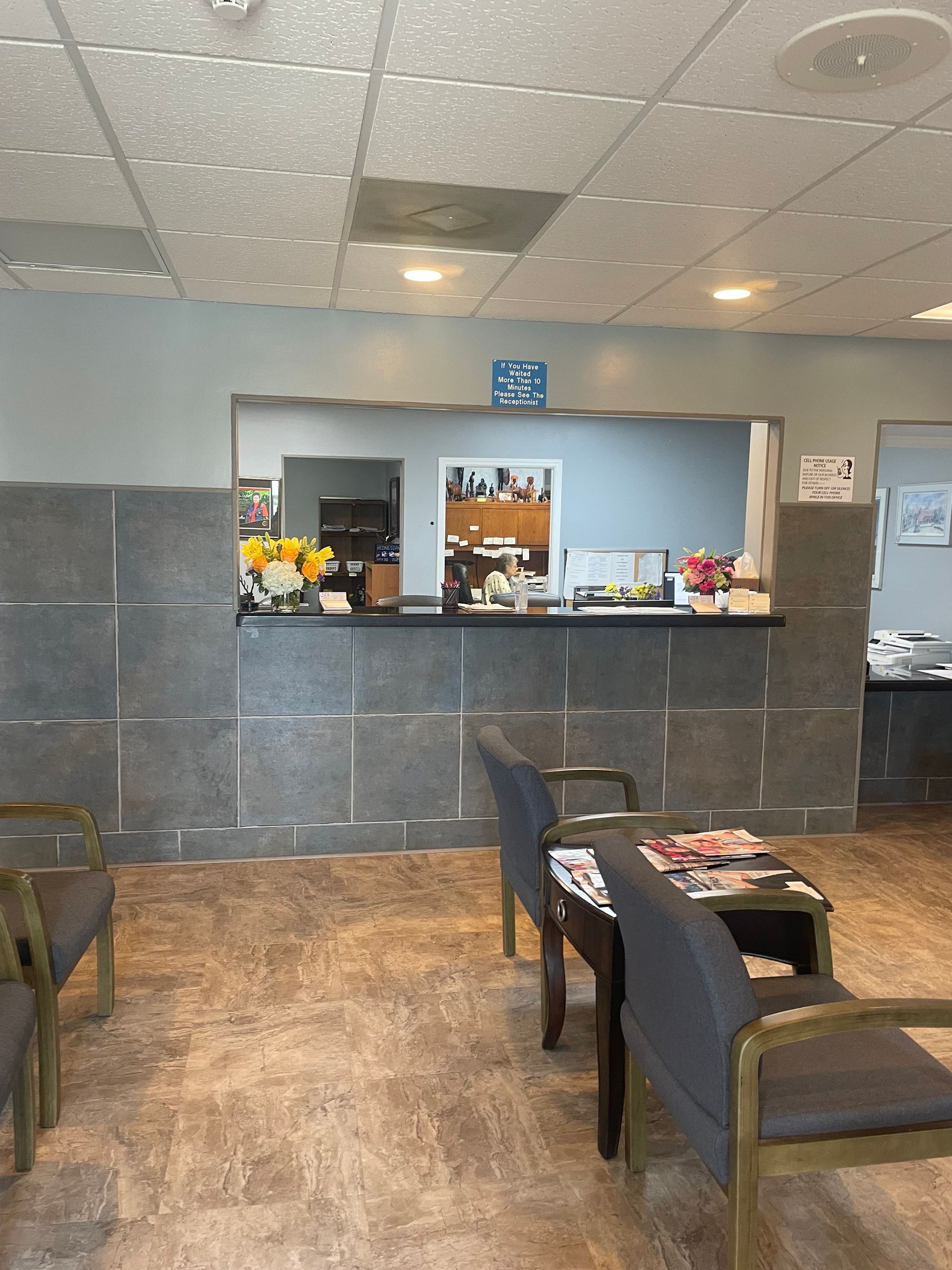 A waiting room with chairs and a counter with a clock on it
