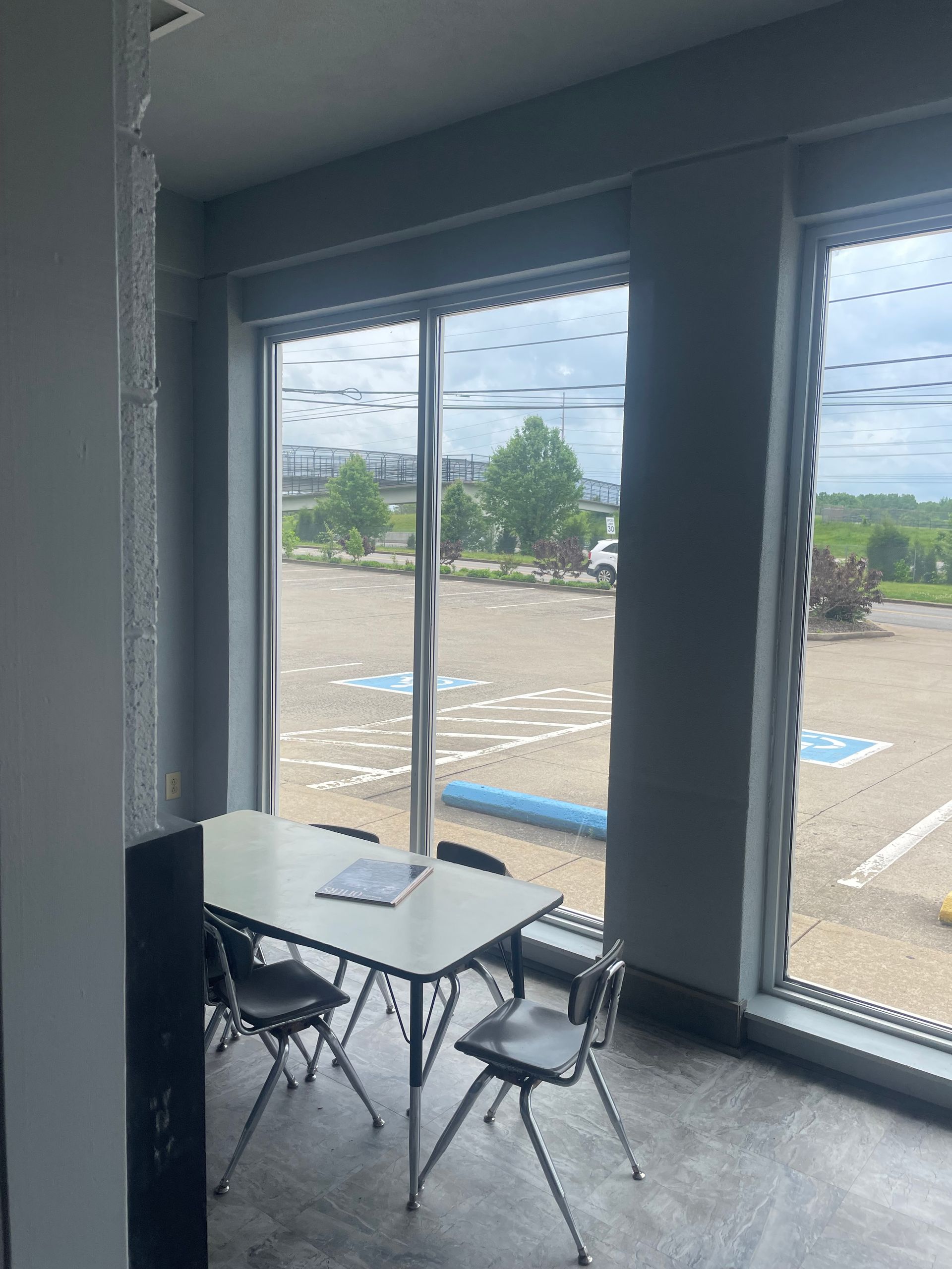 A room with a table and chairs in front of a large window.