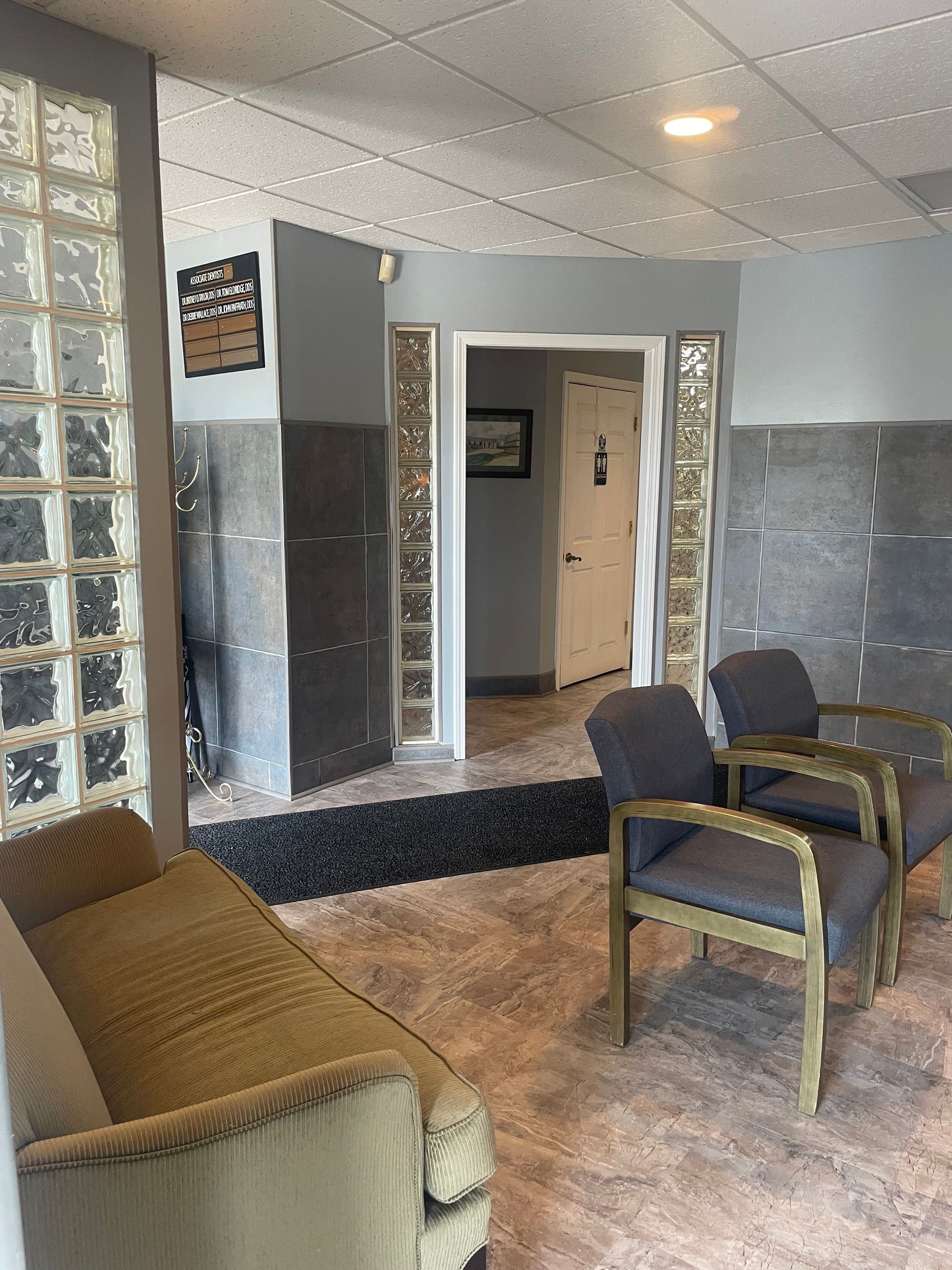 A waiting room with a couch and chairs in a building.