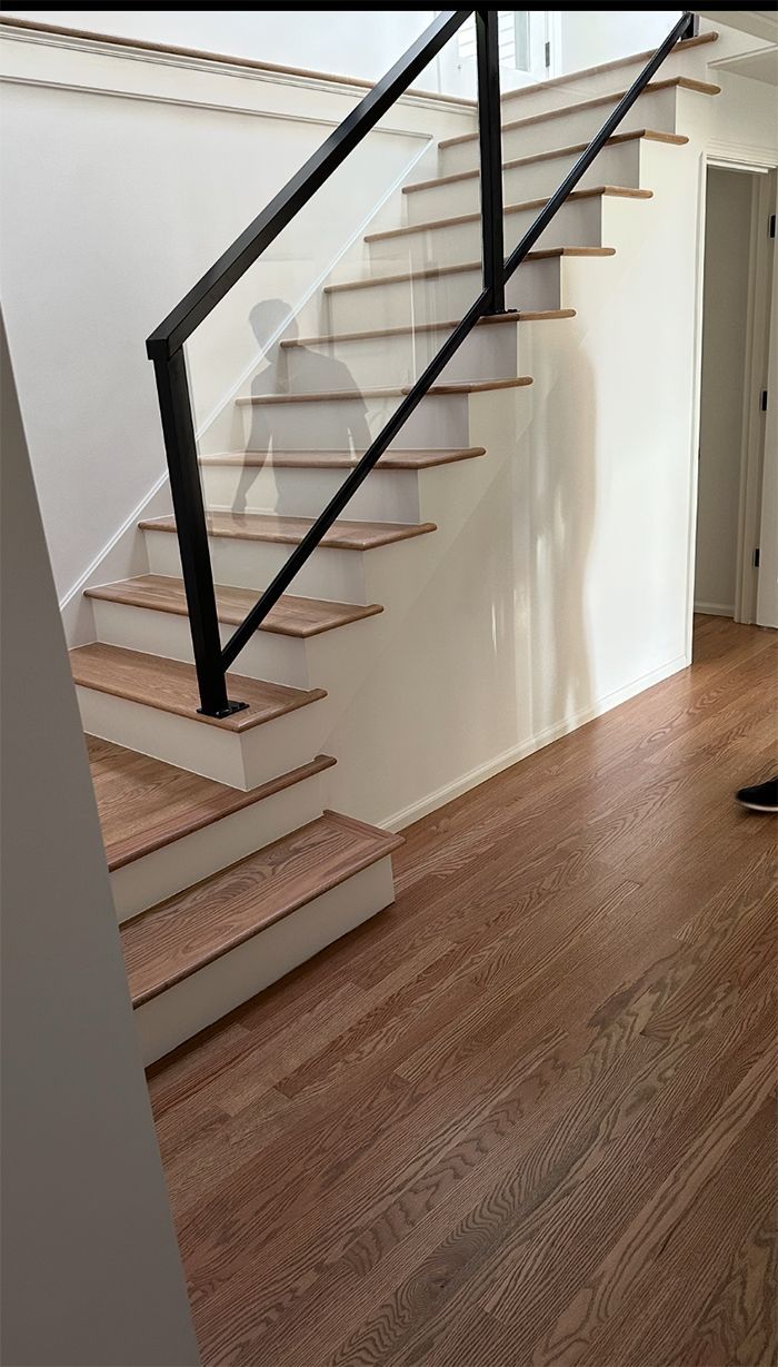 A staircase with wooden steps and a black railing in a hallway.