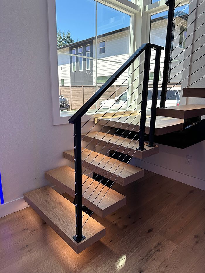 A wooden staircase with a black railing and a window in the background.