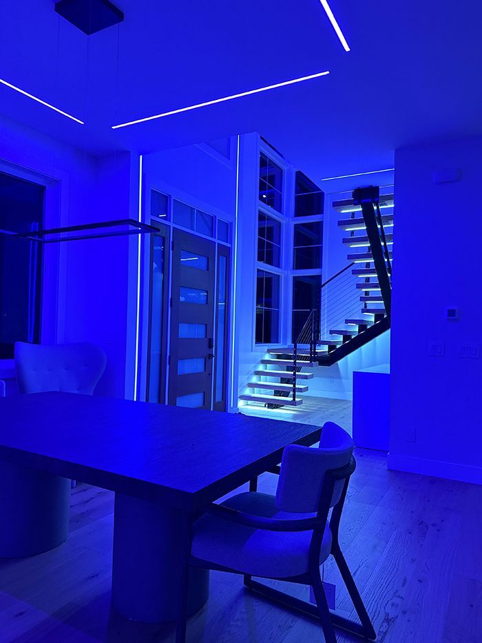 A dining room with a table and chairs and blue lights.