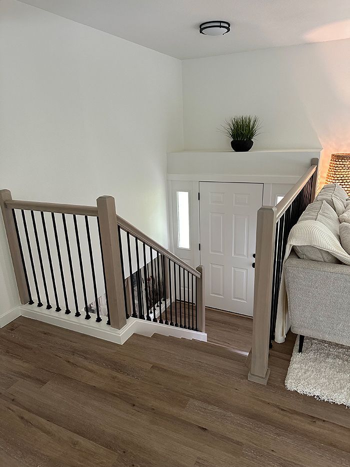 A living room with stairs leading up to the second floor and a couch.