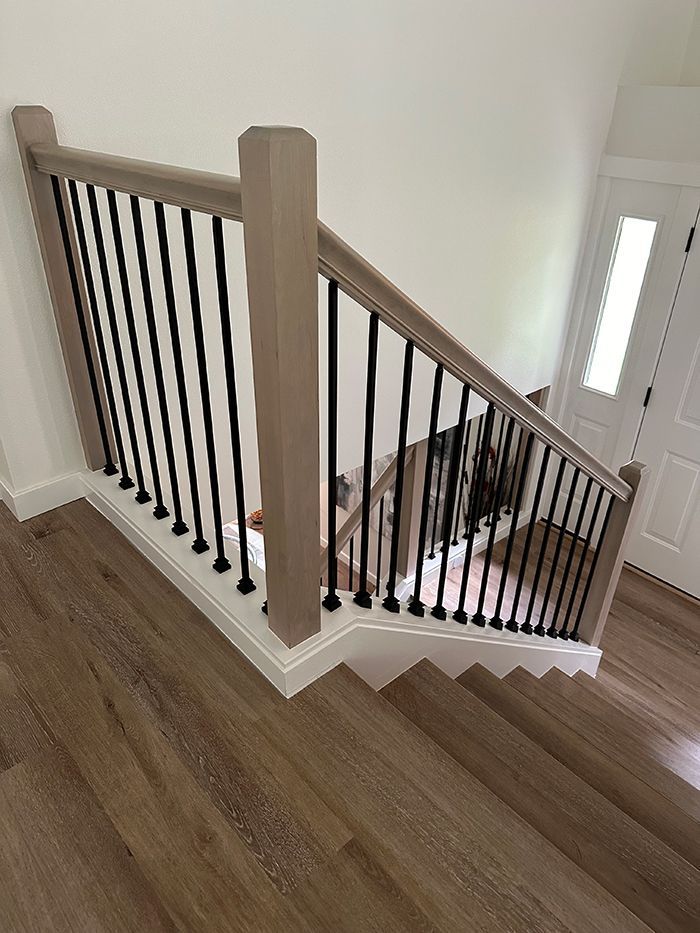 A wooden staircase with a black railing in a house.