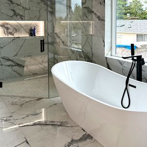A bathroom with a bathtub , shower , and window.