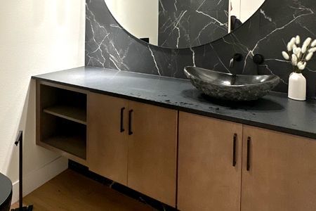 A kitchen with white cabinets and marble counter tops.