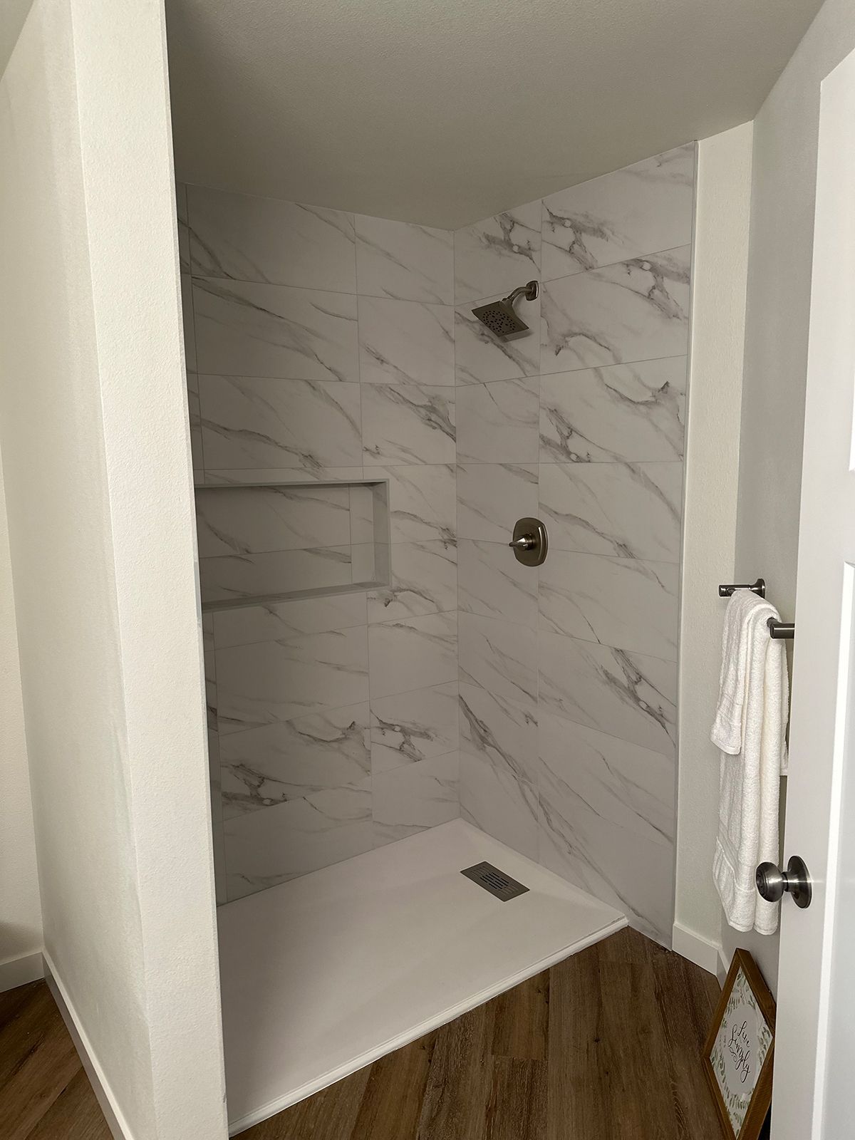 A bathroom with a walk in shower and a towel rack.