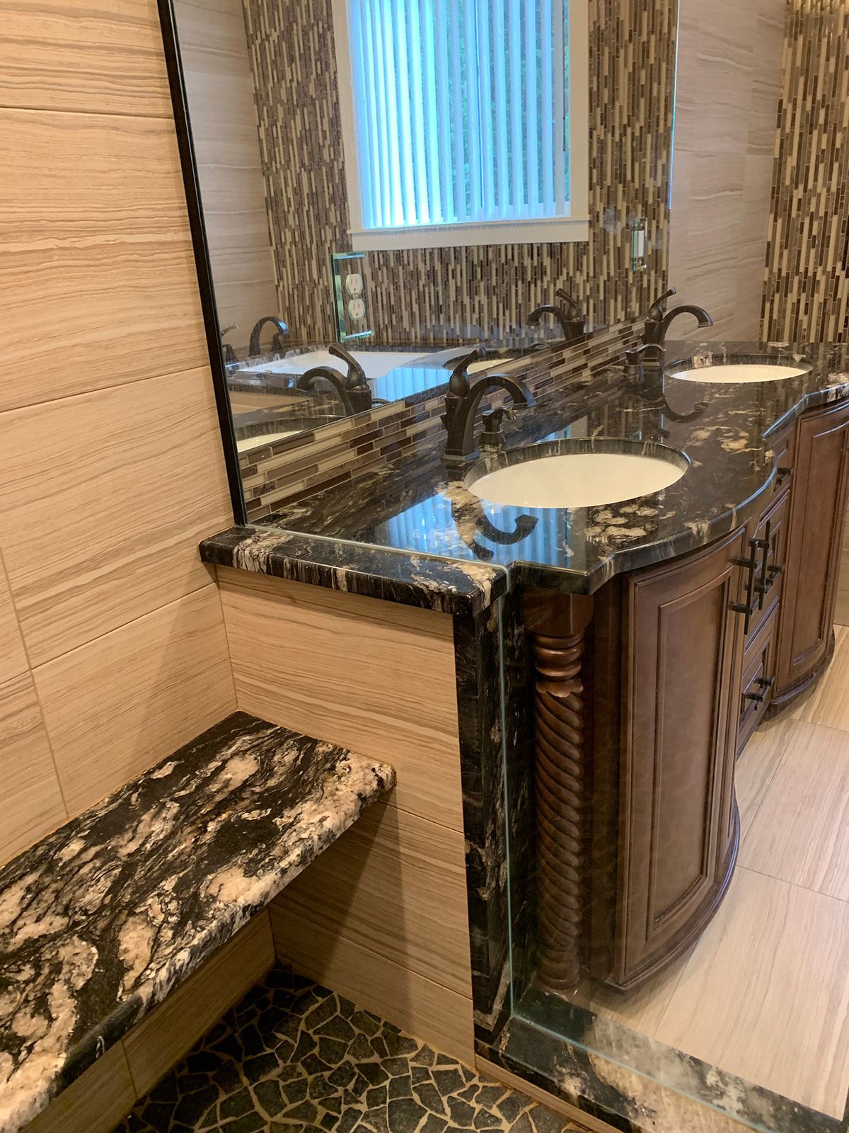 A bathroom with two sinks , a mirror and a bench.