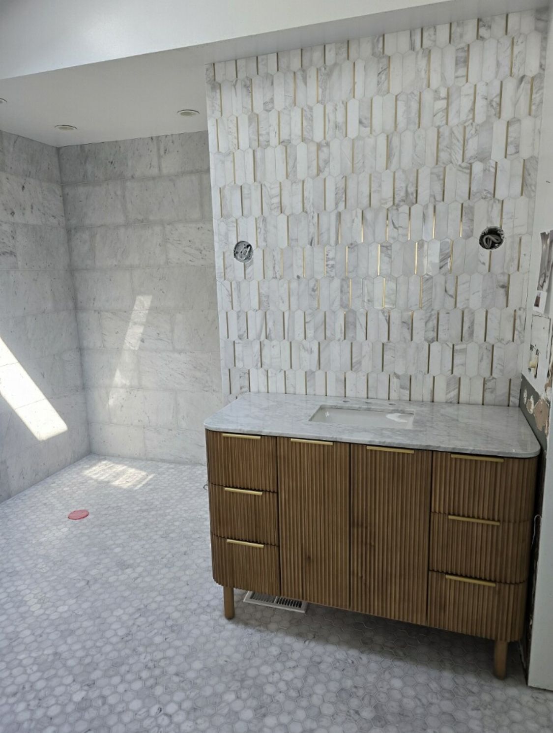 A bathroom with a wooden vanity and a marble counter top.
