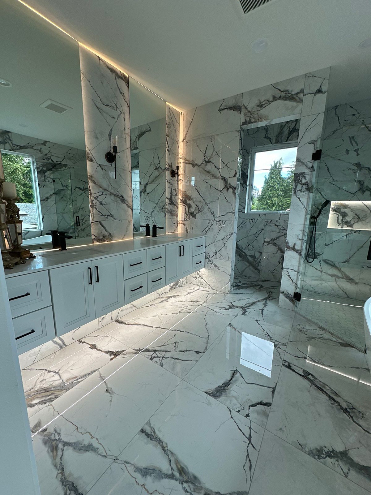 A bathroom with marble tiles and a large mirror.