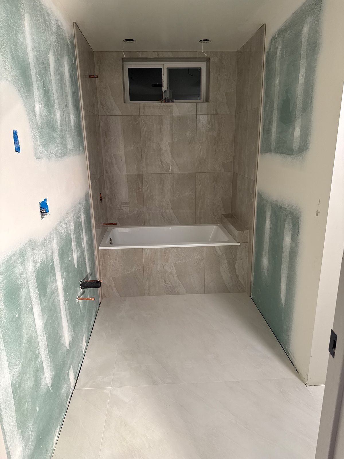 A bathroom under construction with a bathtub and a window.