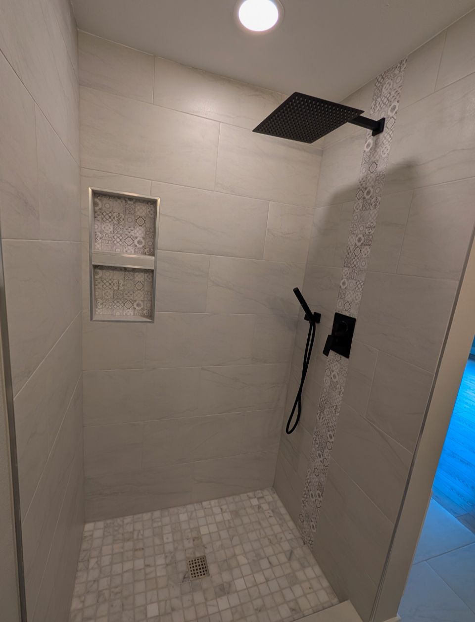 A bathroom with a walk in shower and a black shower head.