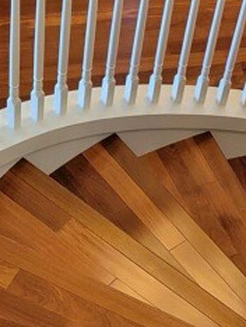 A close up of a wooden spiral staircase with a white railing.